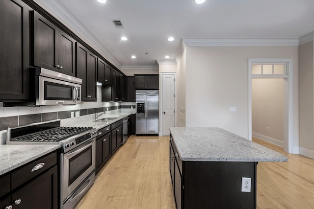 kitchen with light stone countertops, backsplash, stainless steel appliances, crown molding, and a kitchen island