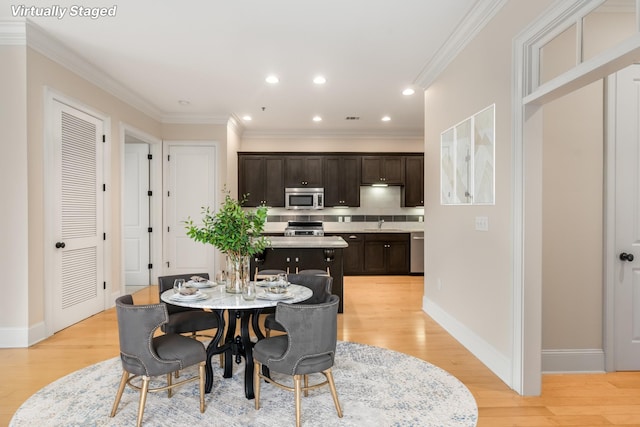 dining space with light hardwood / wood-style floors, ornamental molding, and sink