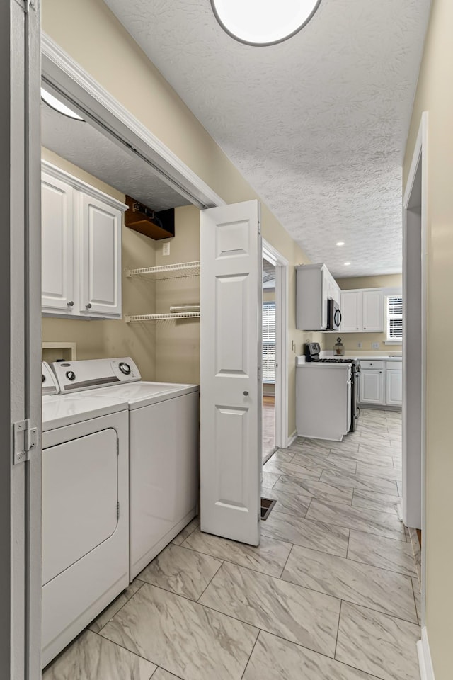 laundry area featuring a textured ceiling and washer and clothes dryer