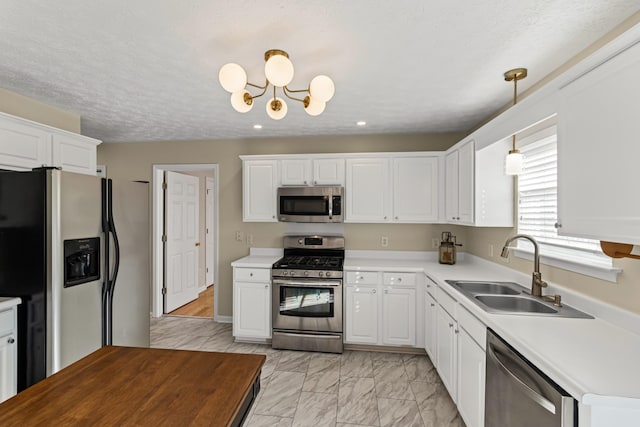 kitchen featuring stainless steel appliances, white cabinets, hanging light fixtures, and sink