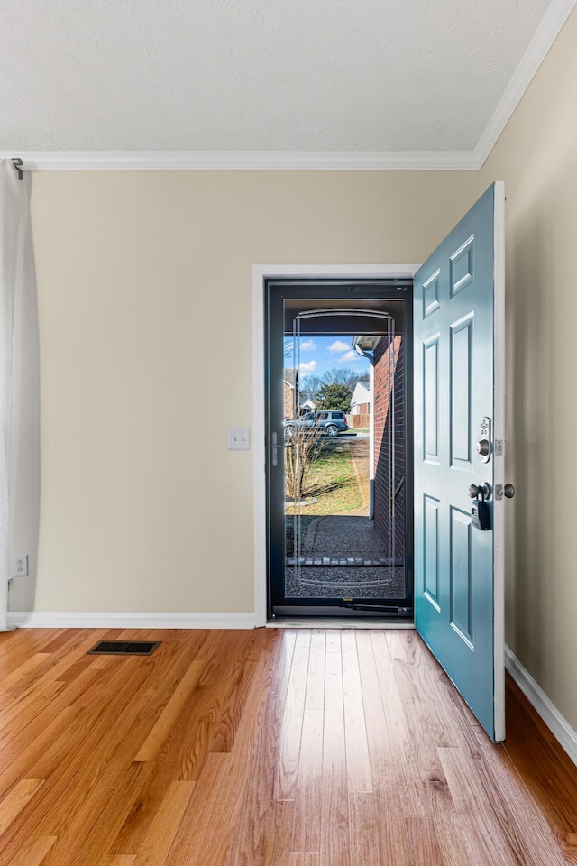 foyer with light hardwood / wood-style flooring and ornamental molding