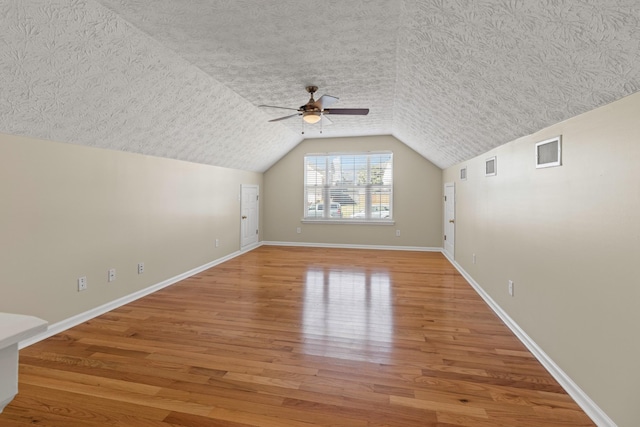 additional living space with hardwood / wood-style flooring, lofted ceiling, and ceiling fan