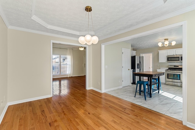 dining area with ceiling fan, a tray ceiling, ornamental molding, and light hardwood / wood-style flooring