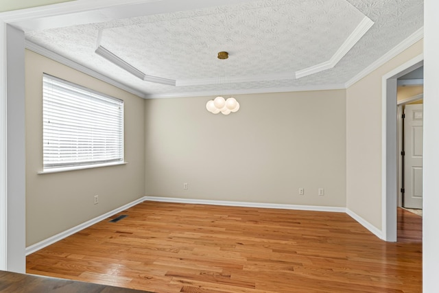 unfurnished room featuring hardwood / wood-style flooring, a textured ceiling, a tray ceiling, and ornamental molding