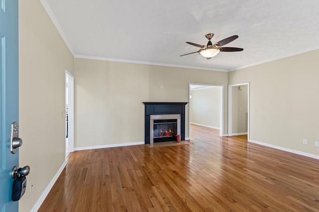 unfurnished living room featuring ceiling fan, ornamental molding, and hardwood / wood-style flooring