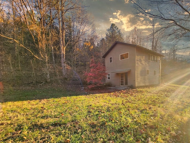 property exterior at dusk featuring a lawn