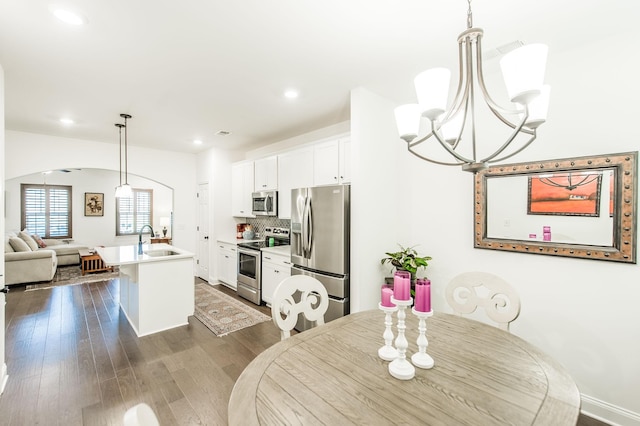 dining area with a chandelier, dark wood-type flooring, and sink