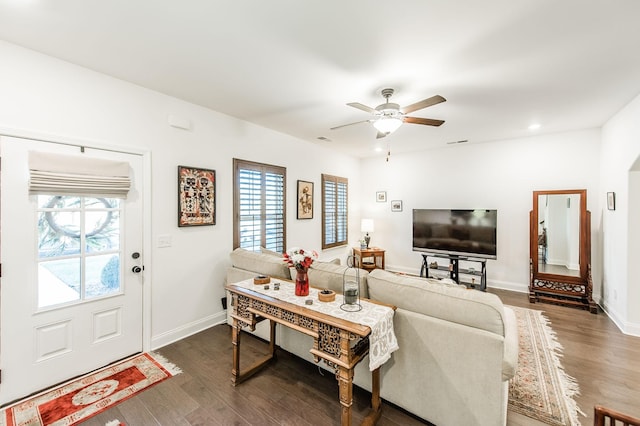 living room featuring a wealth of natural light, ceiling fan, and dark wood-type flooring