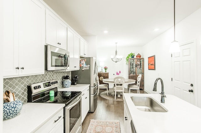 kitchen with tasteful backsplash, stainless steel appliances, sink, decorative light fixtures, and white cabinetry