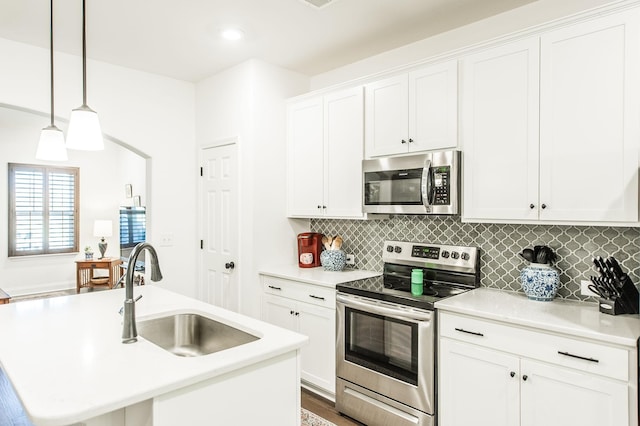 kitchen with hanging light fixtures, sink, white cabinets, and stainless steel appliances