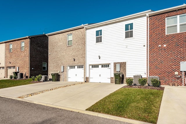 rear view of property with central AC and a garage