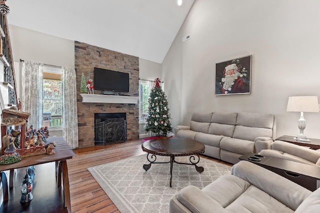 living room with a fireplace, light hardwood / wood-style floors, and high vaulted ceiling