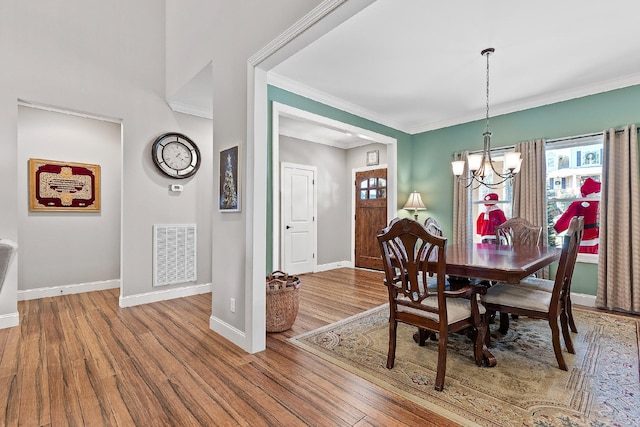 dining area featuring a notable chandelier, wood-type flooring, and ornamental molding