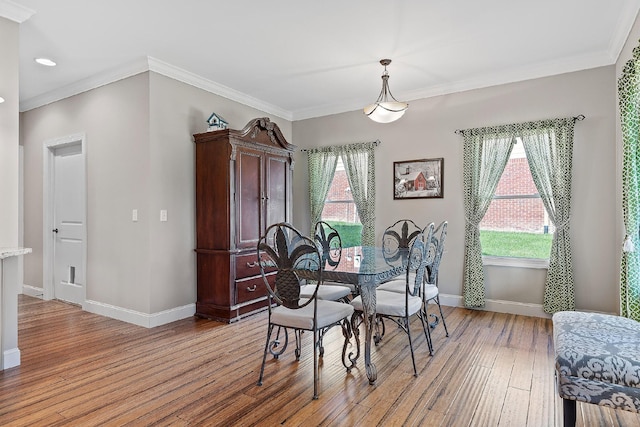 dining room with crown molding and light hardwood / wood-style flooring