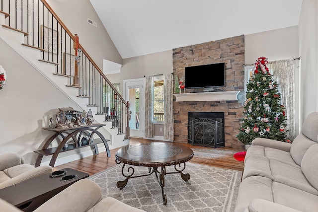 living room featuring a fireplace, high vaulted ceiling, and wood-type flooring