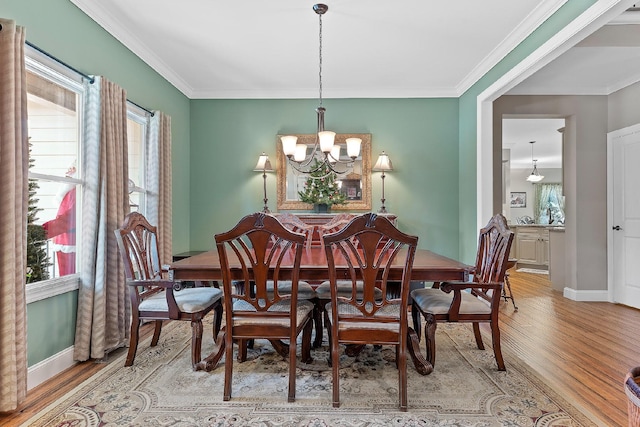 dining area with wood-type flooring, ornamental molding, and a notable chandelier