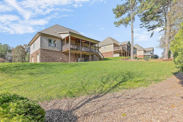 rear view of property with a lawn, ceiling fan, a garage, and a wooden deck