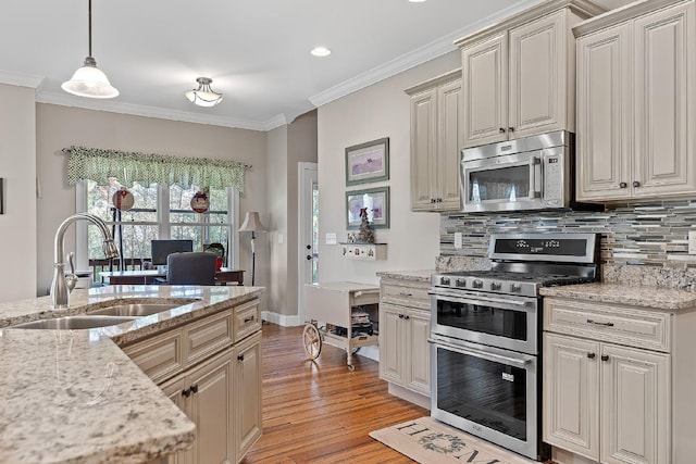 kitchen featuring appliances with stainless steel finishes, light wood-type flooring, ornamental molding, sink, and hanging light fixtures