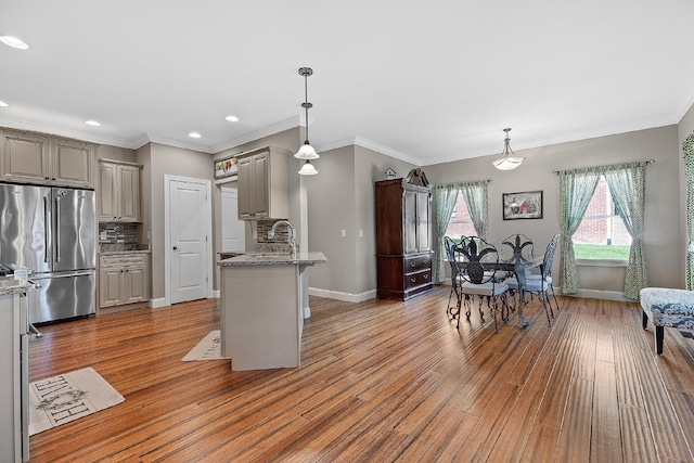 kitchen featuring light stone countertops, stainless steel fridge, backsplash, decorative light fixtures, and dark hardwood / wood-style floors