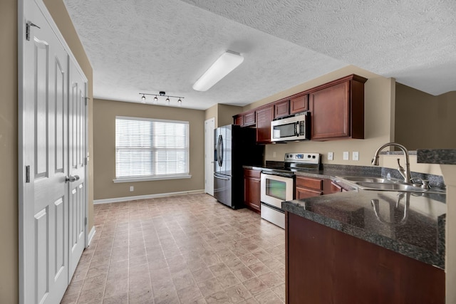 kitchen with sink, rail lighting, a textured ceiling, and appliances with stainless steel finishes