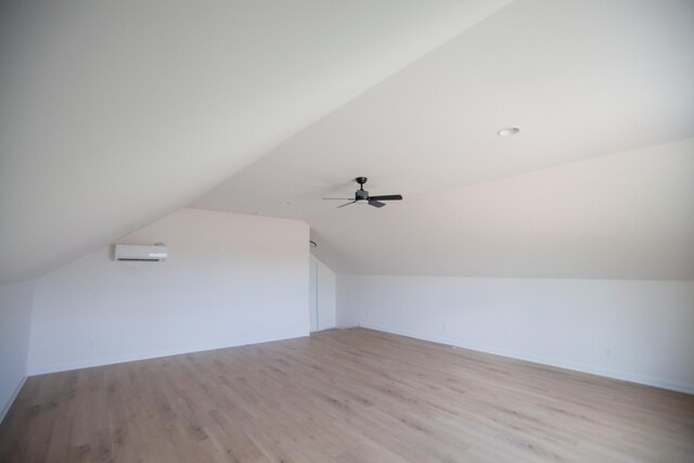 additional living space with ceiling fan, lofted ceiling, a wall mounted AC, and light hardwood / wood-style floors