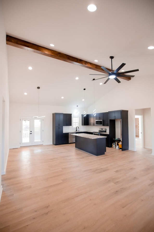 kitchen featuring decorative light fixtures, a center island, beam ceiling, light wood-type flooring, and stainless steel appliances