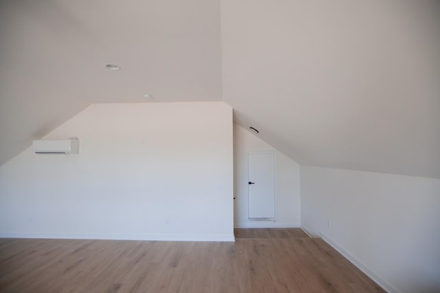 bonus room with lofted ceiling, a wall mounted AC, and light wood-type flooring