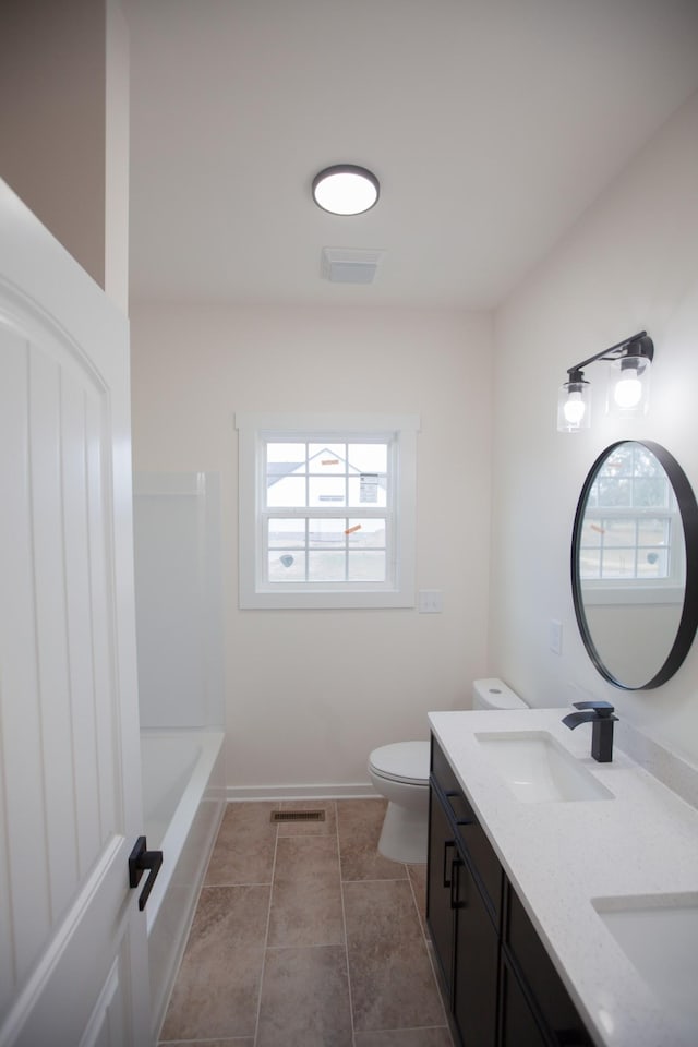 bathroom featuring toilet, vanity, tile patterned flooring, and a wealth of natural light