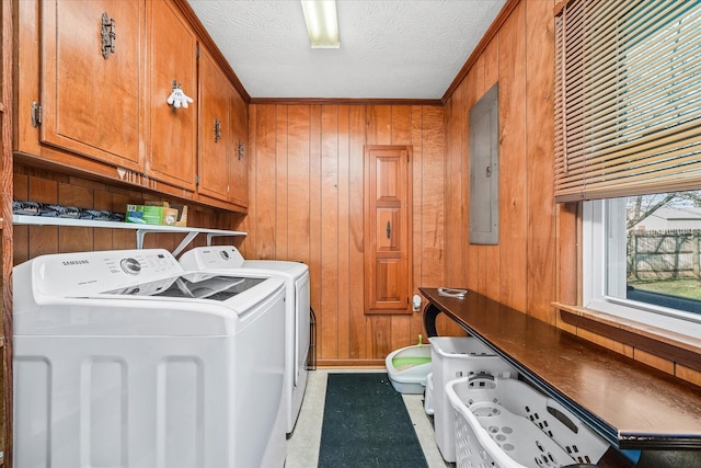 laundry area with electric panel, wood walls, cabinets, and separate washer and dryer