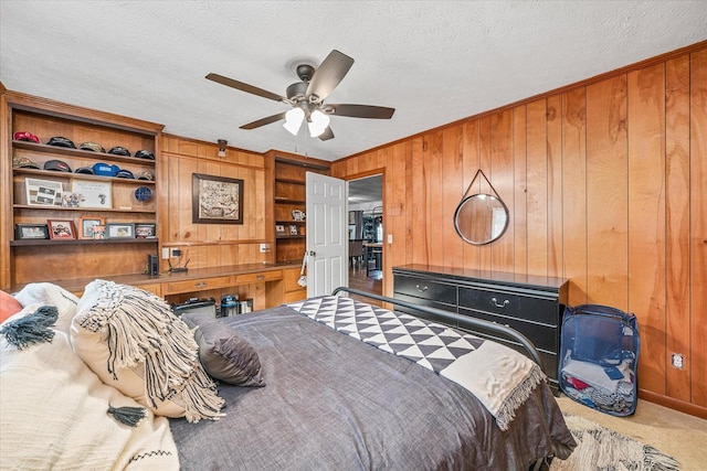 carpeted bedroom with a textured ceiling, ceiling fan, and wooden walls