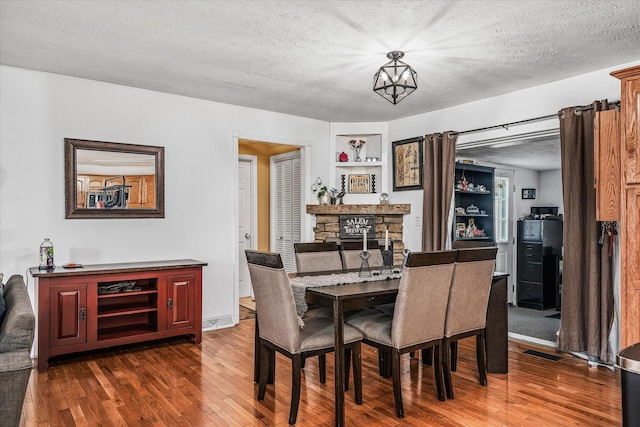 dining space featuring a fireplace, dark wood-type flooring, and a textured ceiling