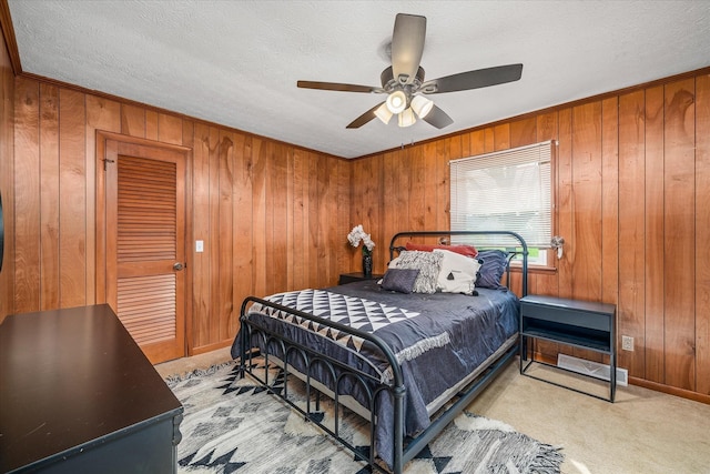 carpeted bedroom featuring ceiling fan, wood walls, a textured ceiling, and a closet