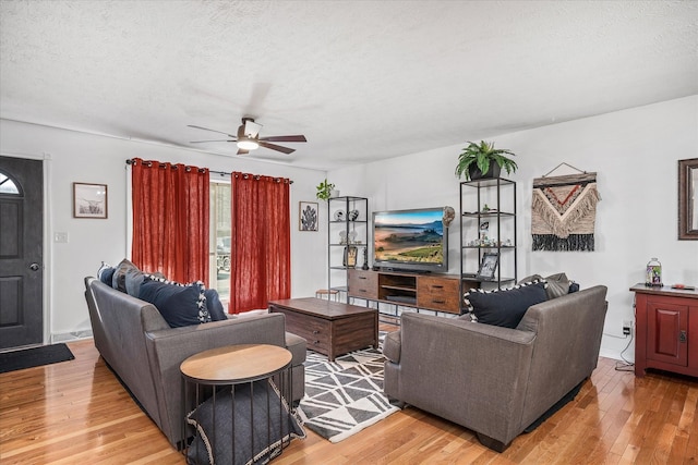 living room featuring a textured ceiling, light wood-type flooring, and ceiling fan