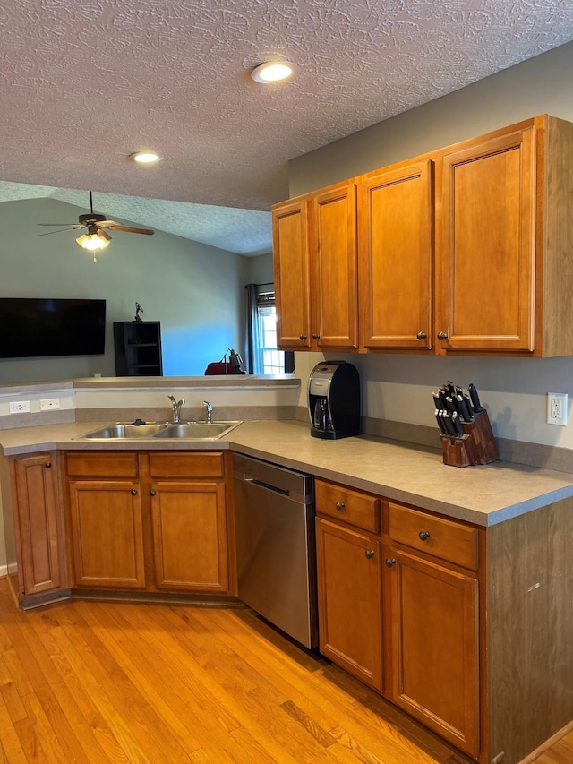 kitchen featuring light wood-type flooring, stainless steel dishwasher, a textured ceiling, ceiling fan, and sink