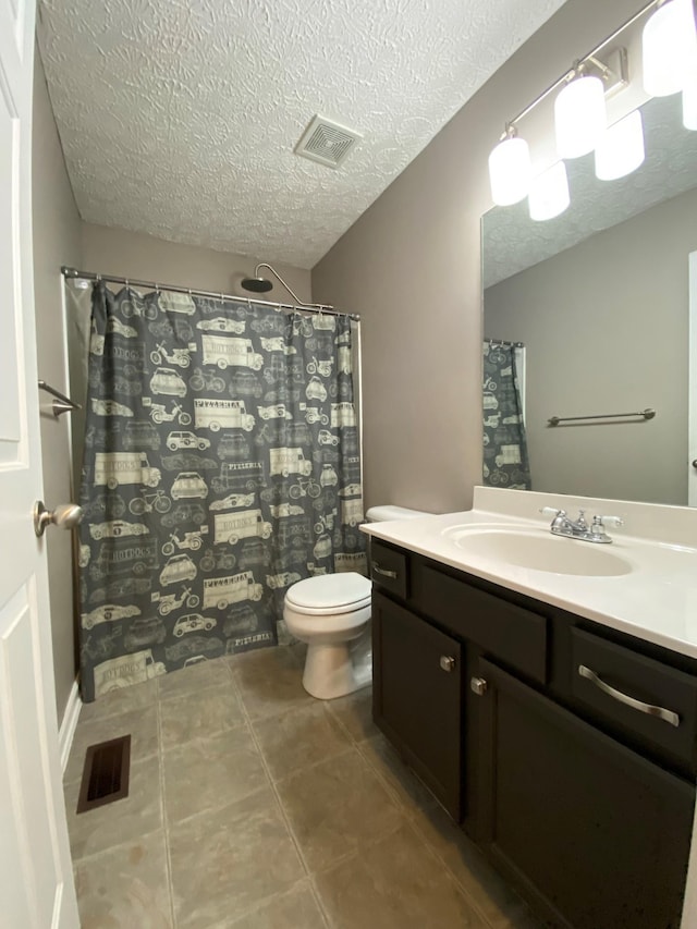 bathroom with tile patterned floors, vanity, a textured ceiling, and toilet