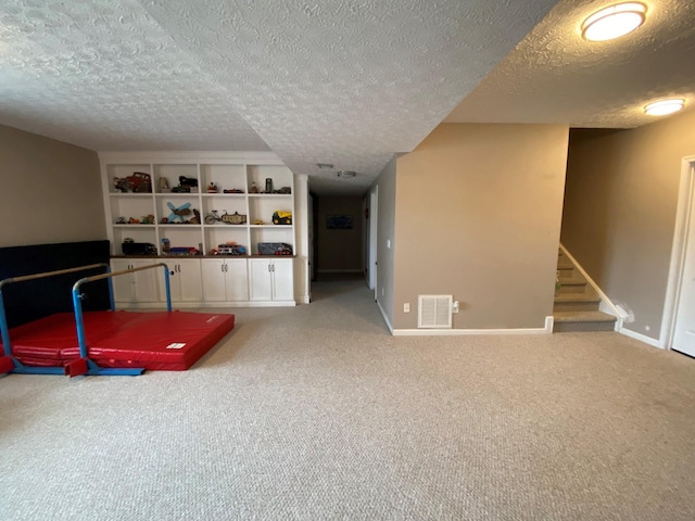 playroom featuring a textured ceiling and light carpet