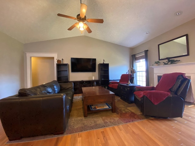 living room featuring wood-type flooring, a textured ceiling, vaulted ceiling, and ceiling fan