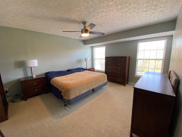 carpeted bedroom featuring ceiling fan and a textured ceiling