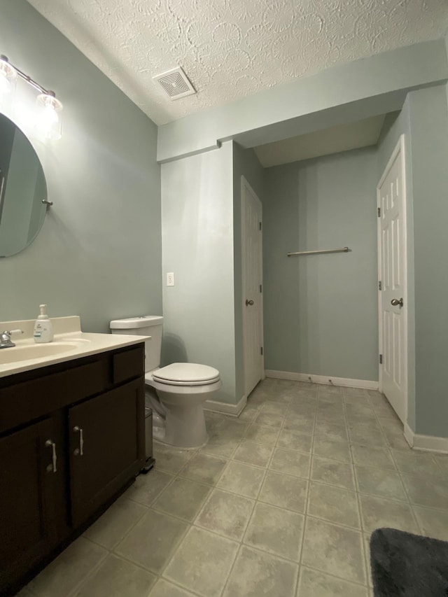 bathroom featuring a textured ceiling, vanity, toilet, and tile patterned floors