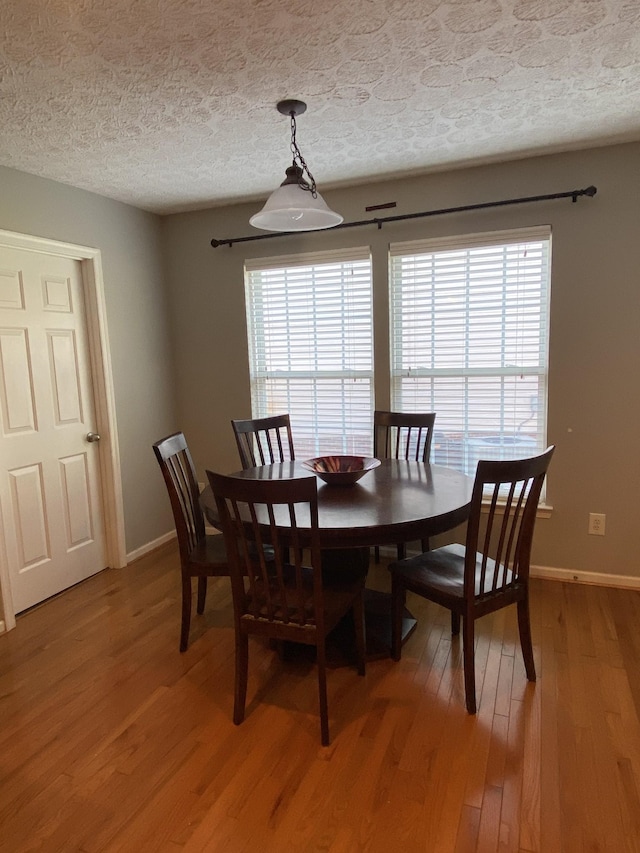 dining space featuring wood-type flooring and a textured ceiling