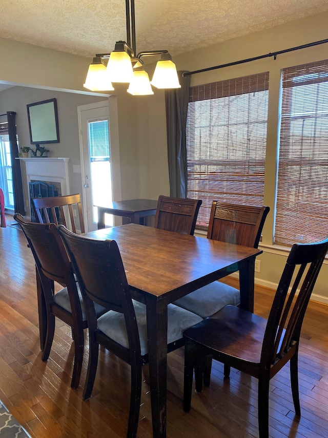 dining area featuring a chandelier, hardwood / wood-style floors, a textured ceiling, and a healthy amount of sunlight