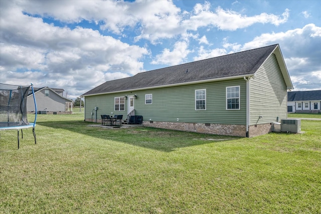 rear view of house featuring a yard, a trampoline, a patio, and central AC unit