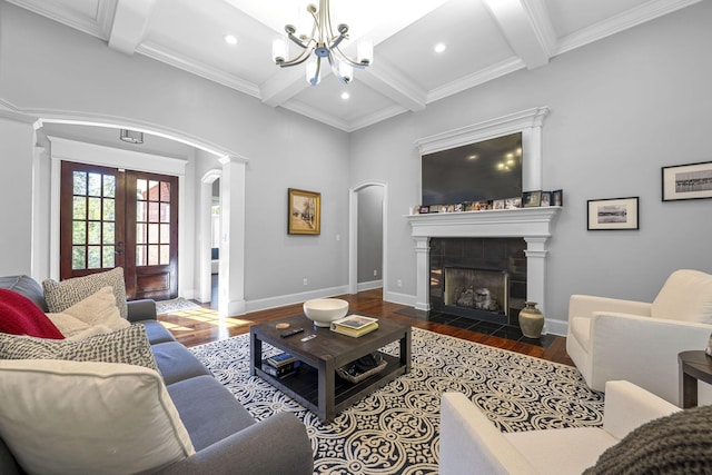 living room featuring beamed ceiling, dark hardwood / wood-style flooring, a fireplace, and a notable chandelier