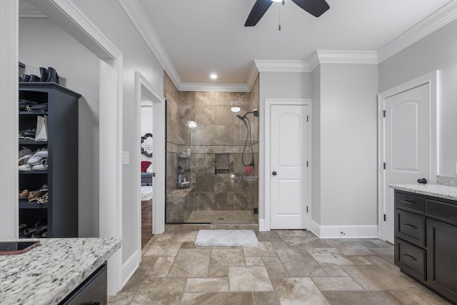 bathroom with a tile shower, vanity, ceiling fan, and ornamental molding