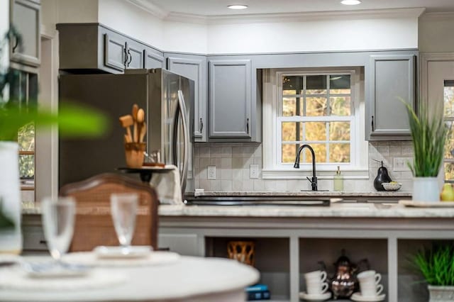 kitchen with gray cabinetry, stainless steel fridge, crown molding, and decorative backsplash