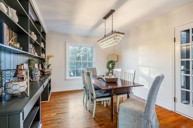 dining room with crown molding, wood-type flooring, and an inviting chandelier