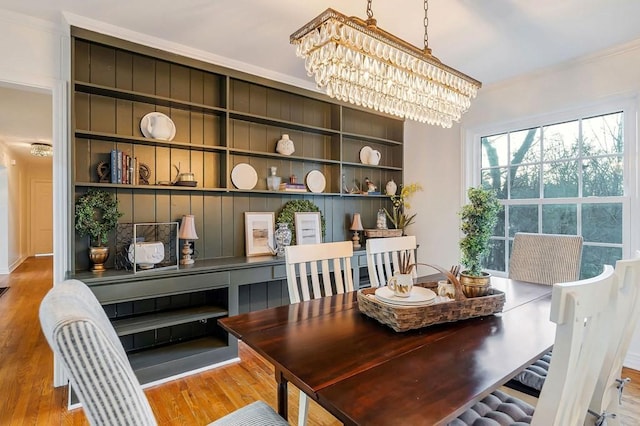 dining area with a chandelier, crown molding, and light hardwood / wood-style flooring