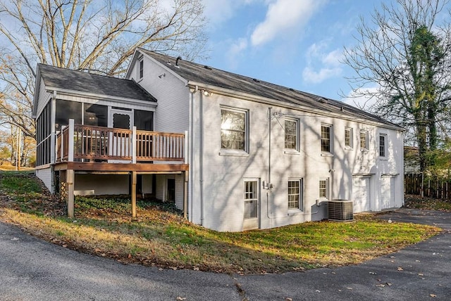 exterior space with central air condition unit, a garage, a deck, and a sunroom