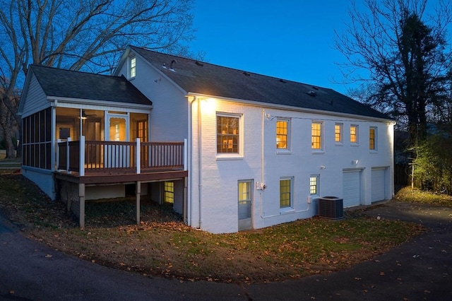 view of property exterior with a sunroom, cooling unit, and a garage