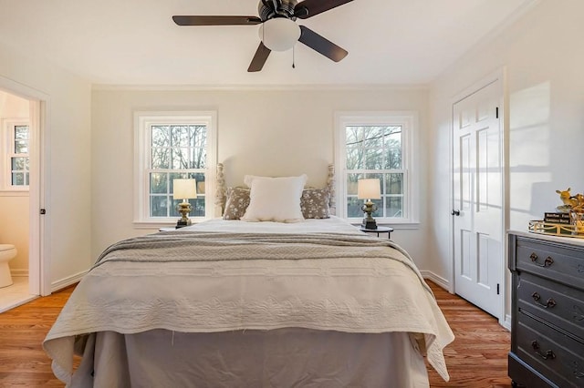 bedroom featuring ensuite bath, ceiling fan, multiple windows, and light wood-type flooring